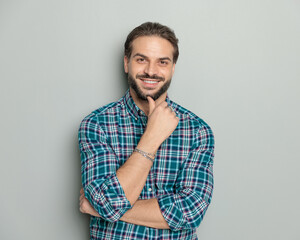 happy casual man in plaid shirt folding arms, touching chin and dreaming