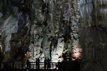 Personas de visita en una cueva gigante iluminada