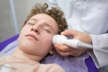 a cosmetologist doctor makes cosmetic procedures on the face of a young guy in a beauty salon