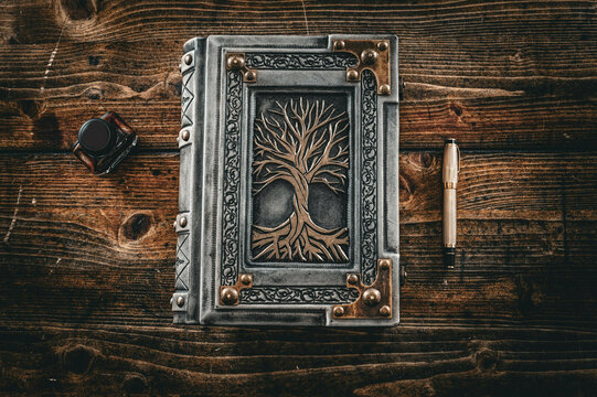 Old weathered white leather book with gilded tree of life captured on old wooden table