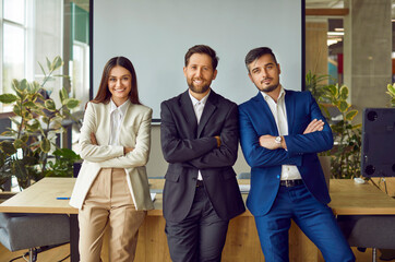 Portrait of a group of happy business people looking cheerful at the camera with crossed arms and...