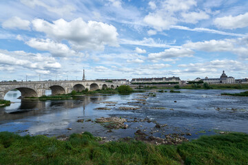 Fototapeta na wymiar A river with a stone bridge crossing it on the left towards a medieval town with a blue sky