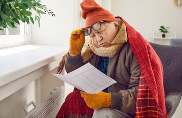 Senior man has problems with paying his heating bills in very cold winter. Old man in hat, gloves...
