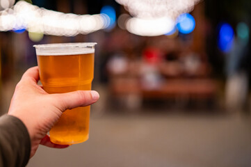 plastic cup glass with beer in hand. Outdoor summer festival