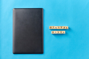digital detox and technology concept - tablet pc or laptop computer and wooden toy block or stamps on blue background