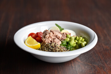 Fresh salad with tuna, quinoa and egg. Poke bowl full of fruit and vegetable vitamins. Fresh edamame, tomato, salad, avocado, lemon