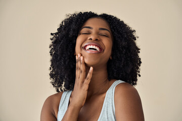 Happy confident young adult African American woman beauty female model, pretty 20s Black lady with curly hair beautiful face advertising skin care laughing isolated at beige background. Authentic shot - obrazy, fototapety, plakaty