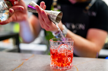 bartender hand making negroni cocktail in bar