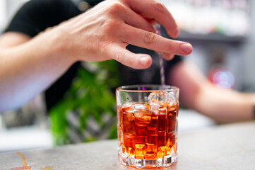 bartender hand making negroni cocktail in bar