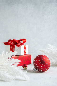 Merry Christmas and Happy Holidays greeting card, frame, banner. New Year. Noel. Christmas red ornaments and gift on light background top view. Winter xmas holiday theme. 
