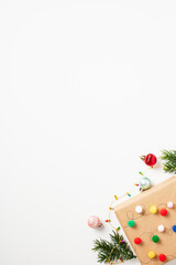 Christmas craft gift box with colorful ornaments, fir branches, balls on white background. Flat lay, top view, space for text. Merry Christmas and Happy New Year vertical banner, invitation design
