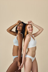 Two happy diverse women, smiling African and Caucasian young girls friends models wearing underwear...