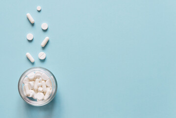 Scattered white pills on blue table. Mock up for special offers as advertising, web background or other ideas. Medical, pharmacy and healthcare concept. Copy space. Empty place for text or logo