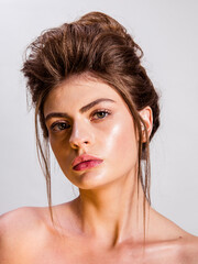Beauty portrait of model with natural make-up and backcombed hair styling on the white background. Fashion shiny highlighter on skin and gloss lips 