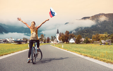 Woman on bike with Sloven flag enjoying beautiful mountain with fog- Sport, tourism,activity concept