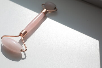 Pink face roller on white background with shades.