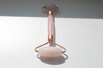 Pink face roller on white background with shades.