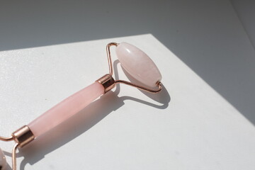 Pink face roller on white background with shades.