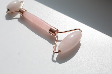 Pink face roller on white background with shades.