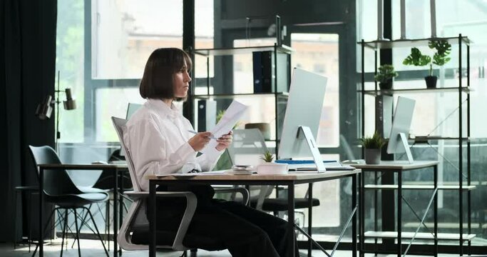 A focused manager reviews documents and cross-references information on a computer screen. Their meticulous attention to detail and commitment to accuracy is evident as they ensure data integrity.