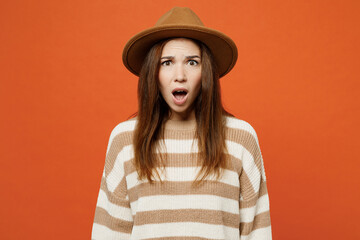 Young sad dissatisfied woman wear striped sweater hat casual clothes look camera with opened mouth scream shout isolated on plain orange red color wall background studio portrait. Lifestyle concept.