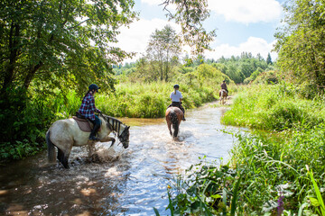 Horse ride, young girls riders, crossing a river, a stream on horseback, splashes from horse...