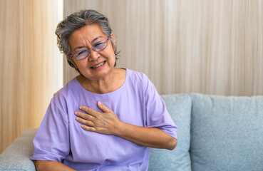 Senior asian adult elderly woman with chest pain suffering from heart attack, health and medical, heart health, heart attack, world heart day, cardiovascular disease.insurance and hospital concept. - obrazy, fototapety, plakaty