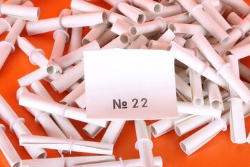 close up of a heap of white tombola tickets with a winning number are lying on an orange ground