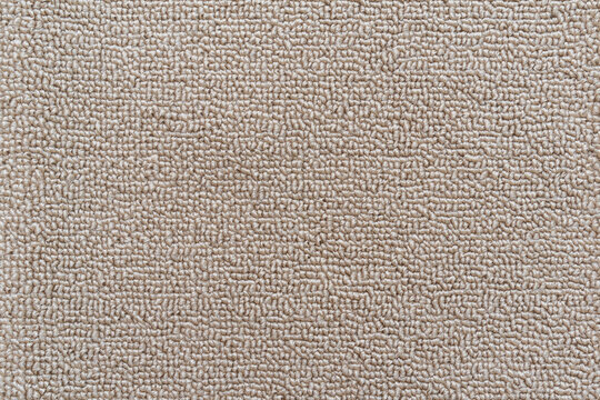 Carpet floor mat or beach towel texture background in sepia beige color made of wool or synthetic fibers, polypropylene, nylon or polyester material