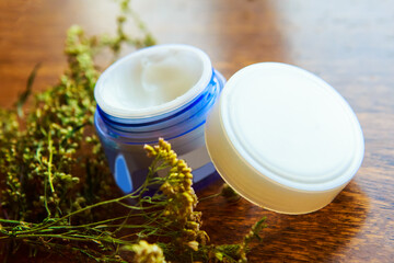 Cream container and herbs on wooden table. Natural beauty product concept