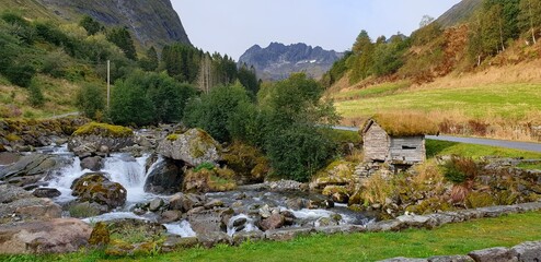 Natural landscape in the mountains. A charming little cottage on a stream in Norway.