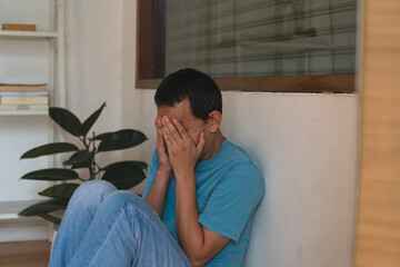 unhappy depressed young man sitting in living room feeling desperate a lonely and sad in mental health depression concept.