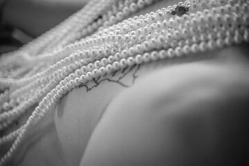 colliers de perles sur le thorax d'un homme tatoué en noir et blanc
