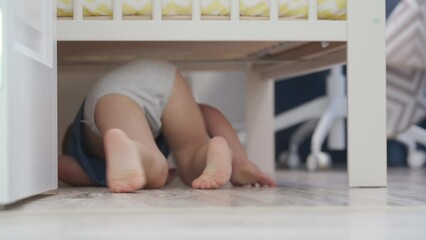 toddler child little boy is hiding under bed in the bedroom