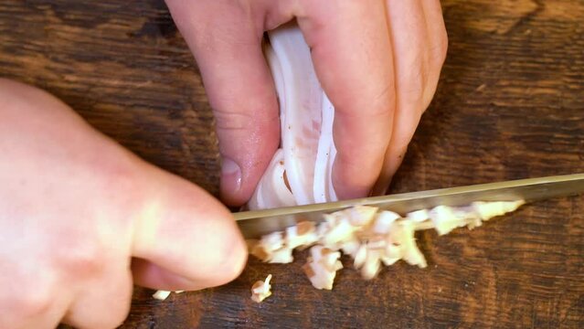 Slicing of salted pork fatback on cutting board, close-up. Ukrainian traditional food - salo