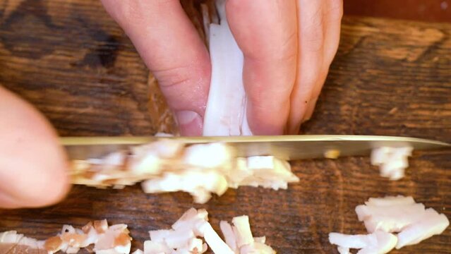 Slicing of salted pork fatback on cutting board, close-up. Ukrainian traditional food - salo