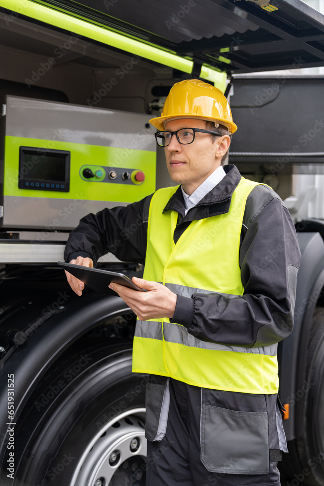 Poster worker with digital tablet operating construction machine equipment.