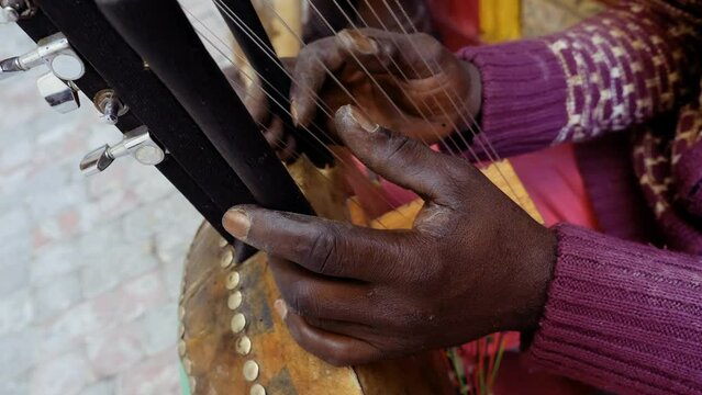 A Senegalese man plays a traditional kora string instrument. Traditional Afro-African music often played in the streets, at weddings, and at festivals. 4k footage.