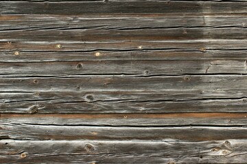 A fragment of a brown old wooden wall. The cracked wooden wall of an old building.
