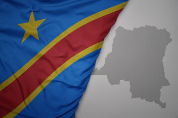 big waving national colorful flag and map of democratic republic of the congo on the gray background.