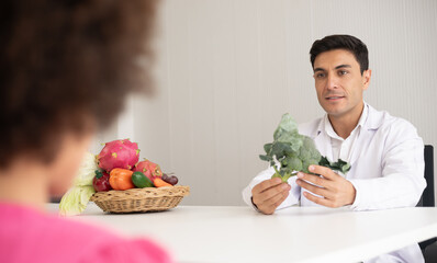 Hispanic nutritionist doctor consulting mixed-race child with her African American mother about a...