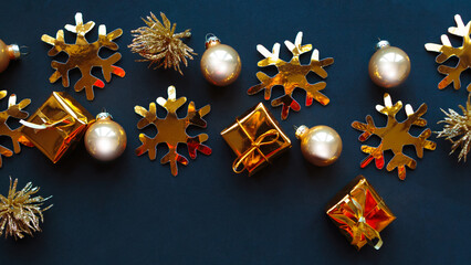 Golden decorations on black background. Flat lay, top view, copy space. Merry Christmas and Happy New Year