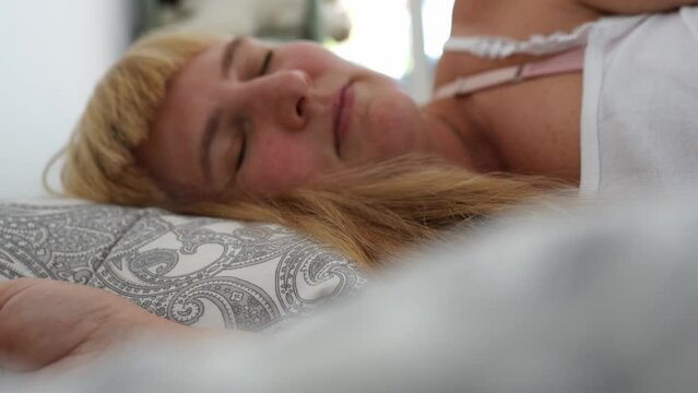 Attractive blonde woman waking up in bed