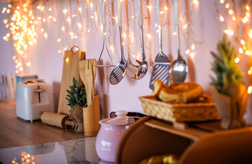 Bread box, cutlery, pink teapot on kitchen table among festive lights. Preparation for Christmas and New Year. Home d cor