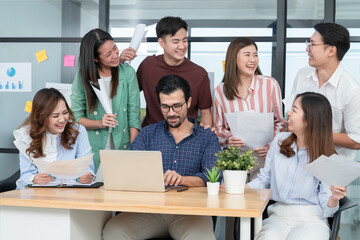 Diverse employees in office having fun during brainstorming while discussing ideas for new project, using laptop. Multiracial coworkers gather in meeting room discuss ideas in group of business people