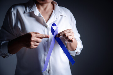 Woman with purple ribbon on grey background, closeup with space for text. Domestic violence awareness. Purple Ribbon for supporting people living. Healthcare and World cancer day concept.