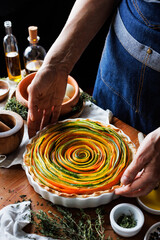 Spiral tart of strips of colorful vegetables in a baking dish ready to be placed in a preheated oven, focus on  inside, close up view