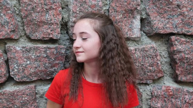 Portrait of teenage girl against background of stone wall. Positive emotions.