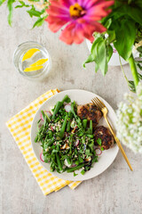 Delicious lunch or breakfast, salad with arugula and asparagus beans, radishes and various seeds, mozzarella cheese and meat patties, top view of food plates and flowers