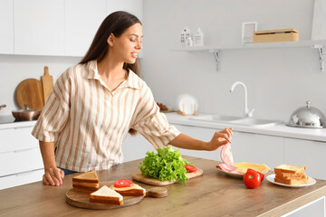 Young woman making tasty sandwich in kitchen